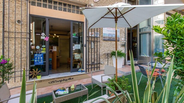 A building with a glass storefront, outdoor seating, and a sign indicating a final liquor license in Italy. - Holiday Apartment Isophylla Standard with Balcony & Wi-Fi (Finale Ligure)