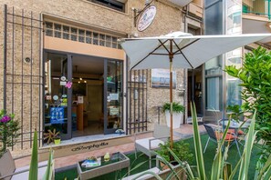 Un edificio con vetrina in vetro, posti a sedere all'aperto e un cartello che indica che l'ultima licenza per la vendita di alcolici in Italia è in arrivo.