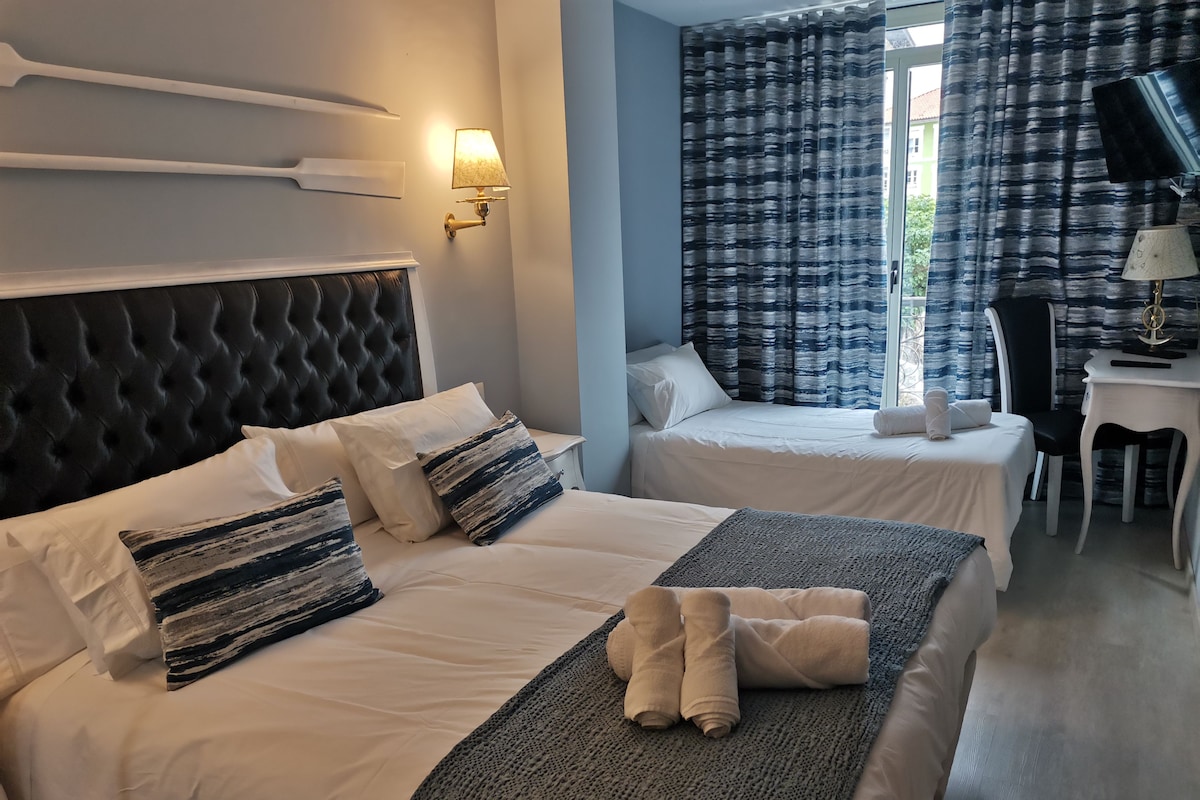 A hotel room with two beds, a desk, and a television.