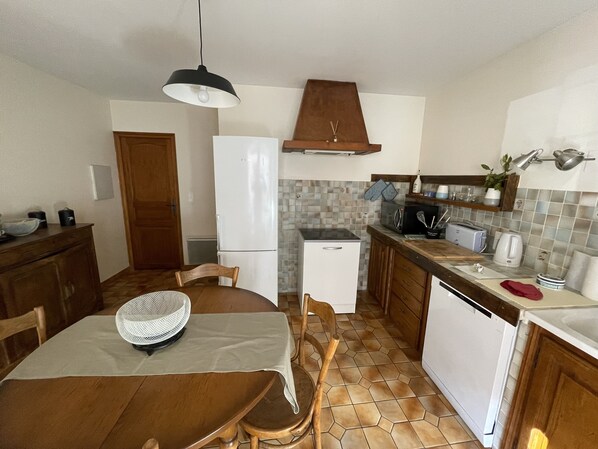 A compact kitchen with a dining area, featuring a refrigerator, microwave, toaster, and a small dishwasher. - La Maison D'augusta (Val Buëch-Méouge)