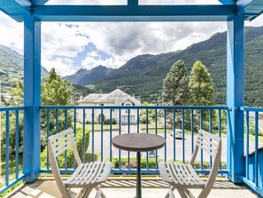 A balcony with a table and two chairs, overlooking a mountain landscape with a house in the background. - T3 calm, 6 pers, terrace, fully equipped (Esquièze-Sère)