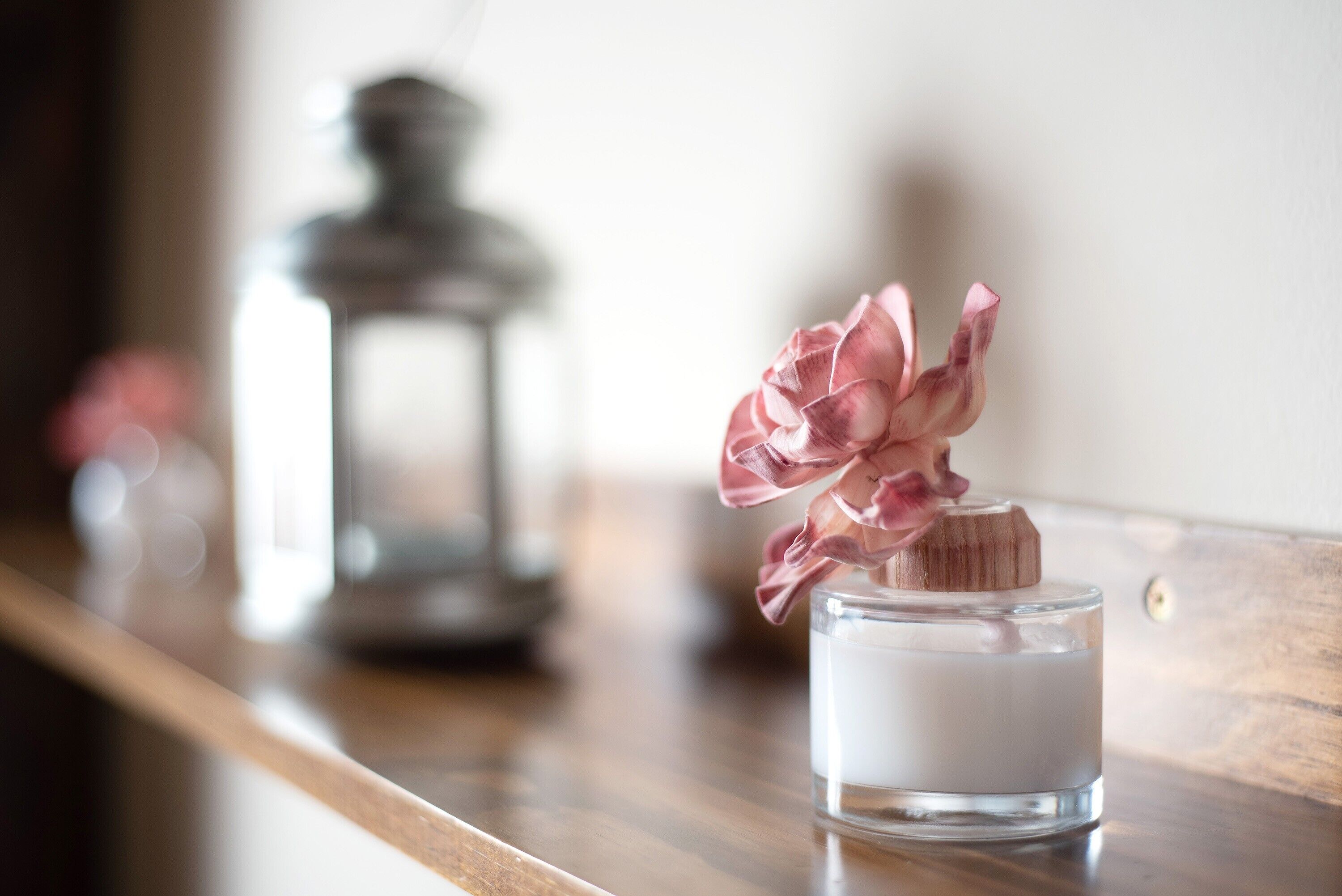Uma vela com uma flor rosa sobre uma superfície de madeira.