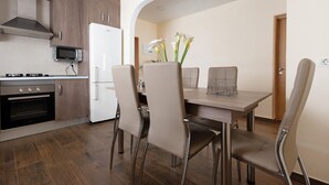 Une cuisine moderne avec un coin repas, comprenant un four à micro-ondes, un four, un réfrigérateur et une table à manger avec des chaises.