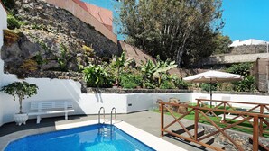 Une piscine avec un banc blanc et une clôture en bois.