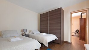 Une chambre d’hôtel avec deux lits, une armoire, une table de chevet et un tapis bleu.
