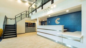 A modern reception area with a staircase, a reception desk, and a blue accent wall.