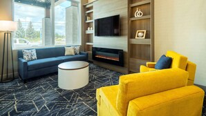 A modern living room with a fireplace, a sofa, a yellow armchair, and a TV mounted on a wooden wall.