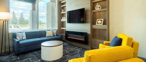 Una sala de estar moderna con chimenea, un sofá, un sillón amarillo y un televisor montado en una pared de madera.