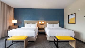 Een hotelkamer met twee bedden, een nachtkastje, een lamp en een schilderij aan de muur.
