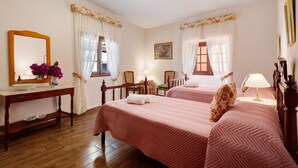 A hotel room with two beds, a wooden dresser, a mirror, a vase with flowers, and a painting on the wall. - Historic 'Casa de Telégrafos' with Mountain Views, Private Terrace & Wi-Fi (vallehermoso)