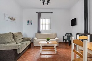 Un salon comprenant un canapé, une table basse avec une plante, un téléviseur fixé au mur et une cheminée.