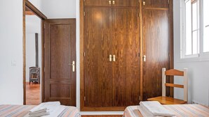 Ein Schlafzimmer mit zwei Betten, einem Holzschrank, einem Stuhl und einem Fenster.