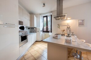 A modern kitchen with white cabinetry, a built-in oven, a microwave, and a large island with a sink.
