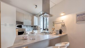 Una cocina moderna con armarios blancos, estufa a gas, microondas y una barra con taburetes.