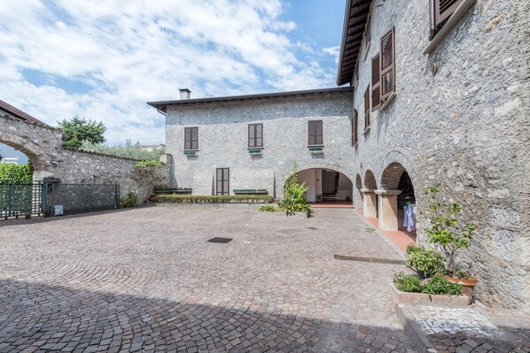 A courtyard with cobblestone flooring, stone walls, and arched doorways.