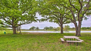Un espace de pique-nique équipé de bancs et d’une balançoire, entouré d’arbres et bordé par un plan d’eau.