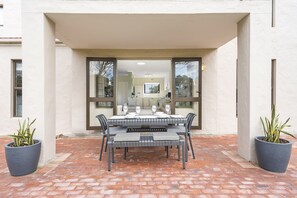 An outdoor dining area with a table set for four, surrounded by chairs with striped cushions. - Laguna Beach B8 (Cape Town)