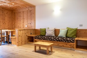 A wooden interior with a sofa, a small table, and a bench. - Rodella A Parte Campitello (Campitello di Fassa)