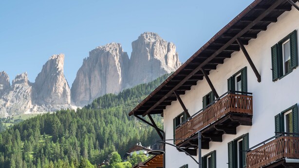 A building with balconies, a mountain backdrop, and a clear sky.