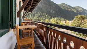 A balcony with wooden furniture, a view of a mountain, and a wooden railing.