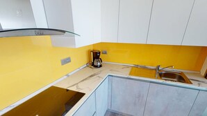 A modern kitchen with a yellow backsplash, a built-in stove, and a sink. - Spacious Studio with Sea View, Terrace, Near Center and Beaches in Menton (Menton)