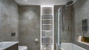 Un baño moderno con ducha de vidrio, inodoro empotrado y bañera independiente.