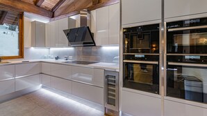 Una cocina moderna con armarios blancos, una campana extractora de acero inoxidable y hornos empotrados.