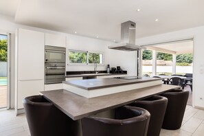 A modern kitchen with a central island, stainless steel appliances, and a view of the outdoors.