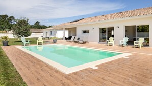 Una piscina con sillones de descanso y un área de patio.