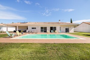 A modern house with a swimming pool, outdoor seating, and a covered patio area.