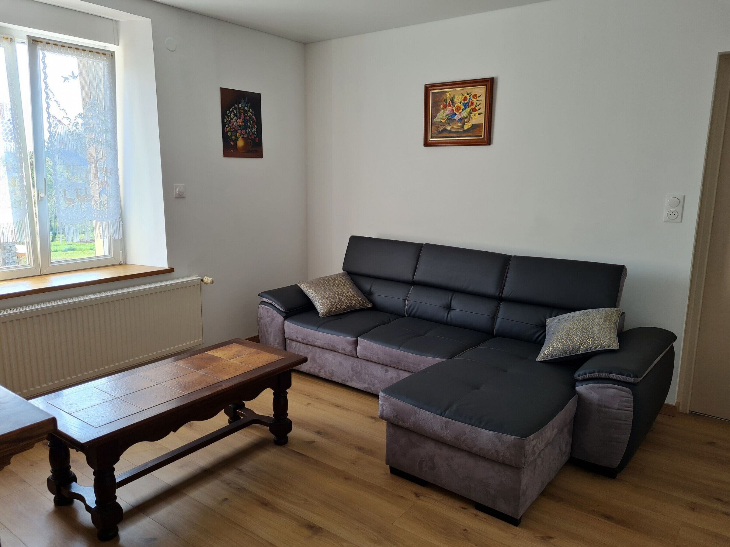 Ein Wohnzimmer mit einer Couch, einem Holztisch und zwei Bildern an der Wand.