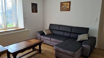 Ein Wohnzimmer mit einer Couch, einem Holztisch und zwei Bildern an der Wand.