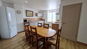 Cocina compacta con mesa, sillas, microondas, lavabo y estufa.