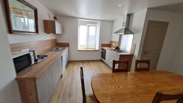 Una cocina compacta con encimeras de madera, microondas integrado y un ventanal que proporciona luz natural.