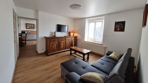 Una sala de estar con sofá, televisión y ventana.