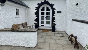 Ein weißes Gebäude mit einem schwarz gerahmten Rundbogen und einer Bank, mit dem Schild "GATE LODGE".