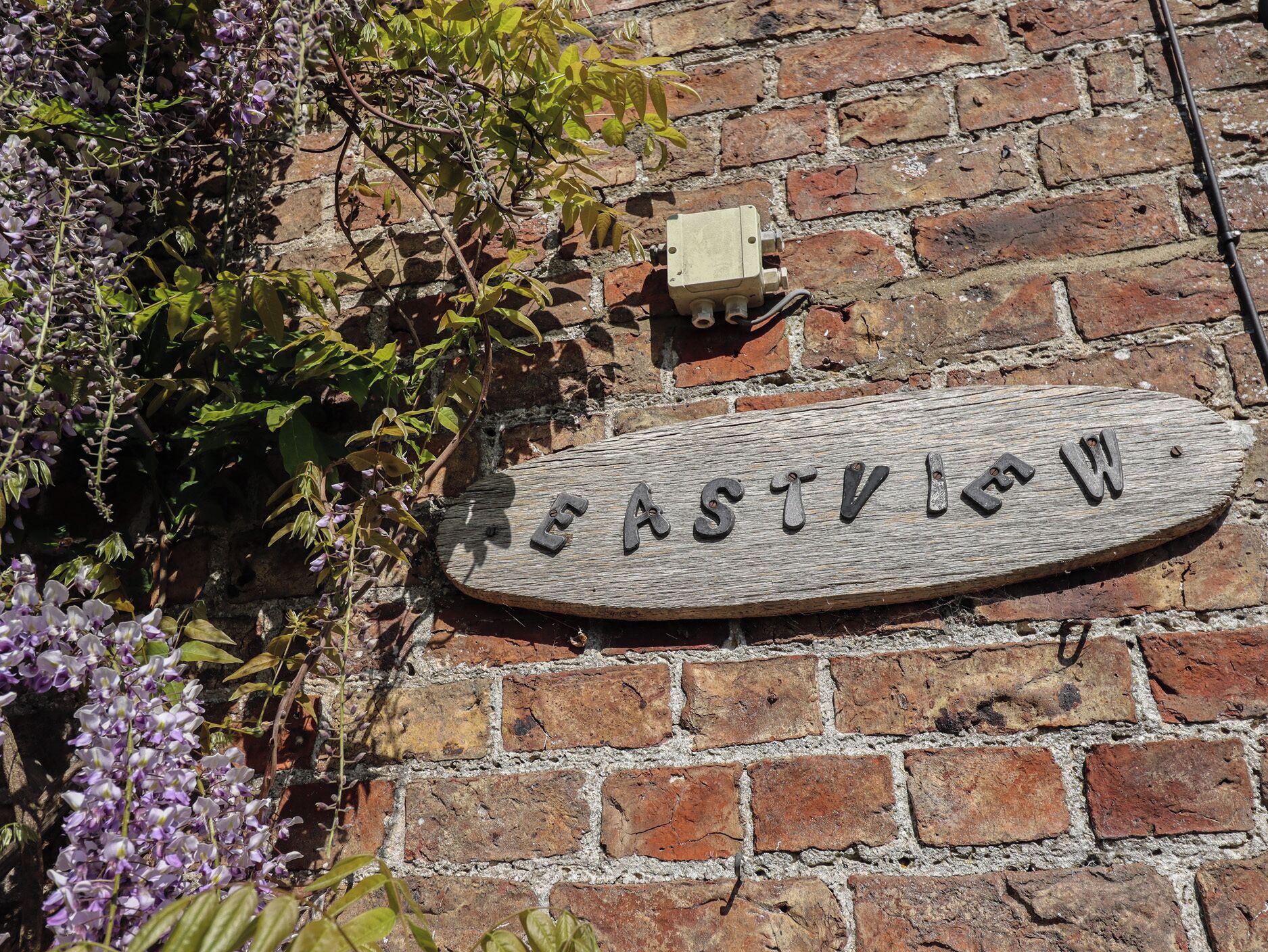 A wooden sign with the name "ASTVILLO" mounted on a brick wall.