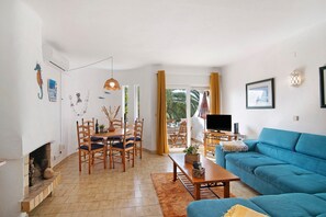 A living room with a blue sofa, wooden dining table, chairs, a fireplace, and a TV.