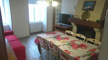 Ein Essbereich mit einem Tisch für vier Personen, einem Fernseher auf einem Schrank und einem Kamin.