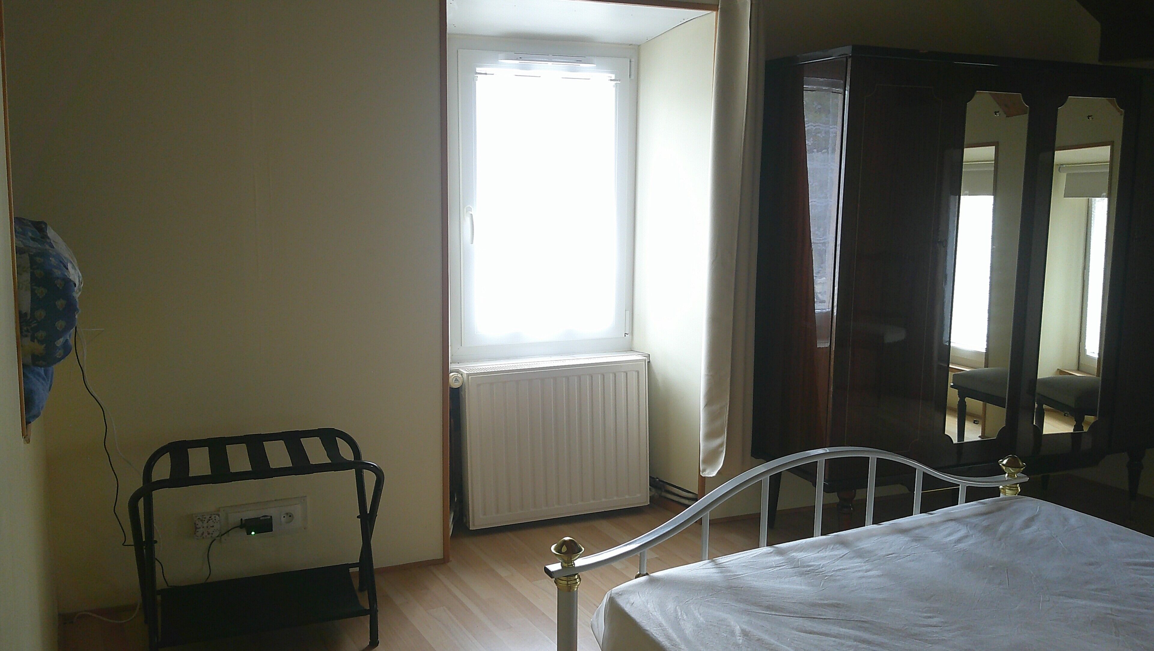 Une pièce comprenant un lit, un radiateur, une fenêtre et une armoire.