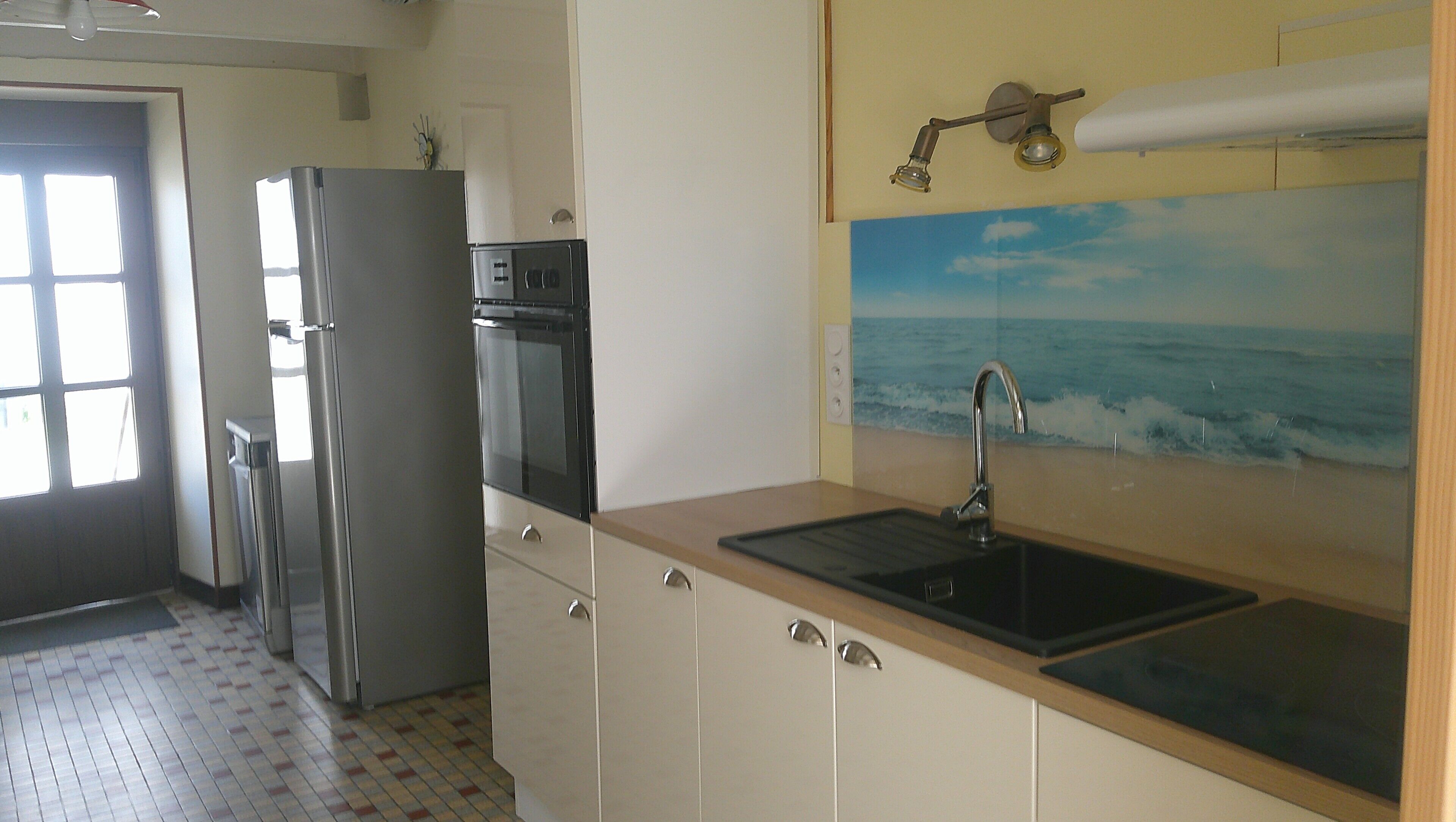 A kitchen with a refrigerator, oven, and sink.