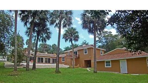 A residential area with a two-story house, a garage, and a lawn with palm trees. - Guest House with pool, boat parking (Leesburg)