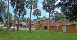 A residential area with a two-story house, a garage, and a lawn with palm trees. - Guest House with pool, boat parking (Leesburg)