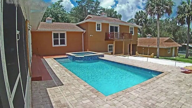 A swimming pool with a hot tub, surrounded by a brick patio, and a house with a balcony. - Guest House with pool, boat parking (Leesburg)