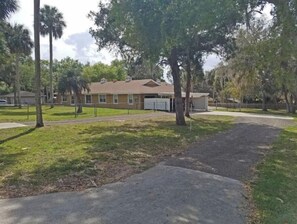 A single-story house with a garage, surrounded by a grassy lawn and trees.