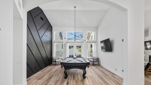 A billiards table in a room with wooden flooring, white walls, and a large window. - Black Palm! Sparkling Pool, Pool Table, Close To Kierland Entertainment, Newly Designed Beauty! (Scottsdale)