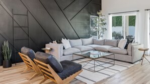 A modern living room with a sectional sofa, wooden chairs, a glass coffee table, and a large window with curtains. - Black Palm! Sparkling Pool, Pool Table, Close To Kierland Entertainment, Newly Designed Beauty! (Scottsdale)