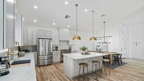 A modern kitchen with white cabinetry, stainless steel appliances, and a central island with stools. - Black Palm! Sparkling Pool, Pool Table, Close To Kierland Entertainment, Newly Designed Beauty! (Scottsdale)