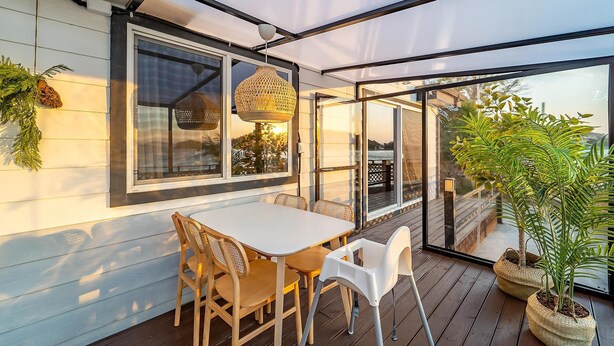A covered patio with a table and chairs, large windows, and potted plants. - Yeosu Hi Mom Kids Family Pension Gold (Yeosu)