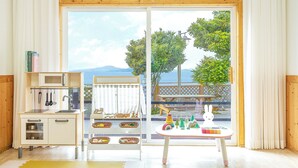 A kitchen with a microwave, sink, and cabinets, a dining area with a table and chairs, and a view of the sea through large glass doors. - Yeosu Hi Mom Kids Family Pension Gold (Yeosu)